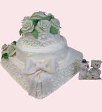 Трёхъярусный свадебный торт с бантом из мастики, розочками и фигурками медвежат: белая основа, оригинальное сочетание прямоугольного и круглых ярусов